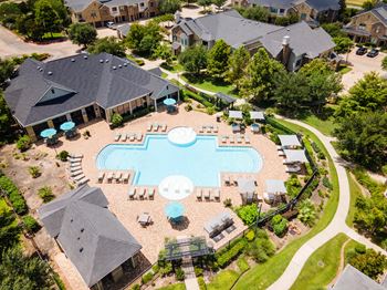 An aerial view of a swimming pool surrounded by houses and trees.